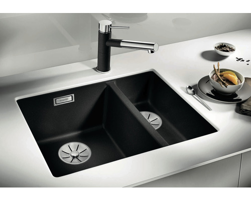 Zwarte dubbele spoelbak van composietmateriaal met kraan op een wit aanrechtblad