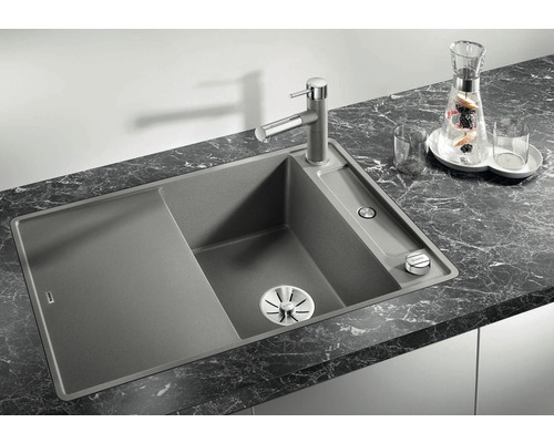 Granieten spoelbak met afdruiprek en kraan op een werkblad.