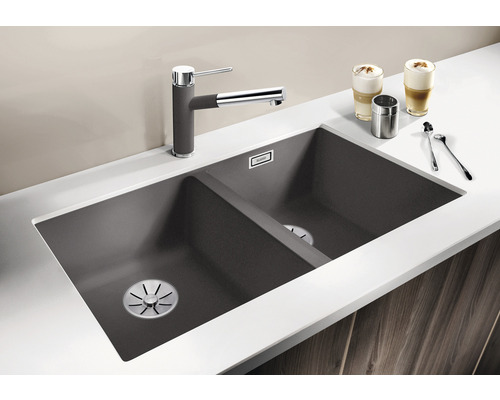 Spoelbak met twee bakken, kraan en keukengerei op een werkblad.