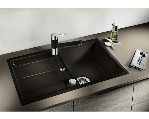 Donkere gootsteen met afdruiprek en kraan op een aanrecht.