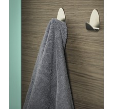 Handdoek aan een zilverkleurige zelfklevende haak aan een houten wand