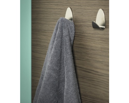 Handdoek aan een zilverkleurige zelfklevende haak aan een houten wand