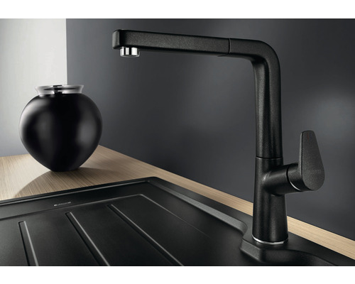 Zwarte keukenkraan met uittrekbare sproeikop naast gootsteen en decoratie