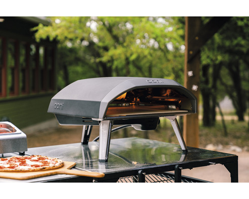 Ooni pizzaoven met pizza op een houten plank