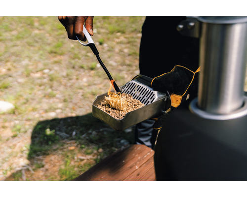 Een persoon steekt houtpellets aan met een aansteker in een schep.