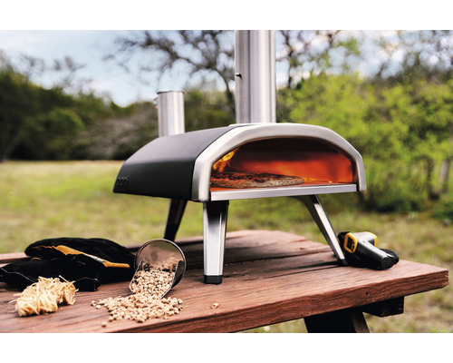 Pizzaoven met accessoires op een houten tafel buiten