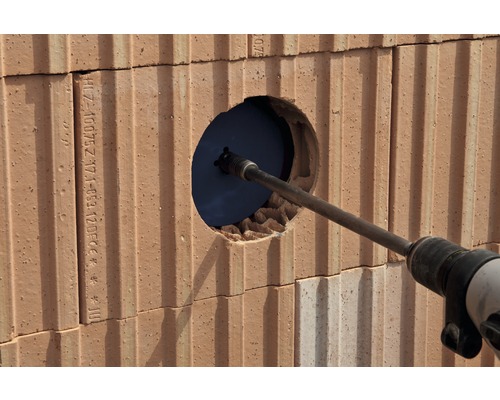 Boormachine boort gat in bakstenen muur