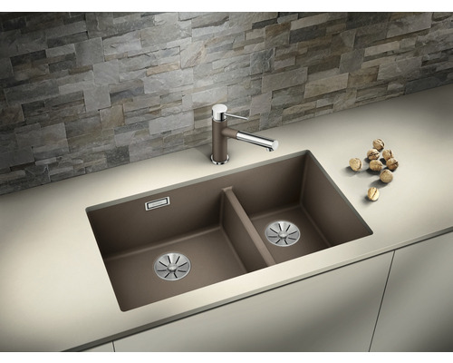 Dubbele spoelbak met kraan op een aanrecht voor een stenen muur