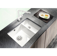 Keuken spoelbak met afdruiprek en kraan op donker aanrechtblad.