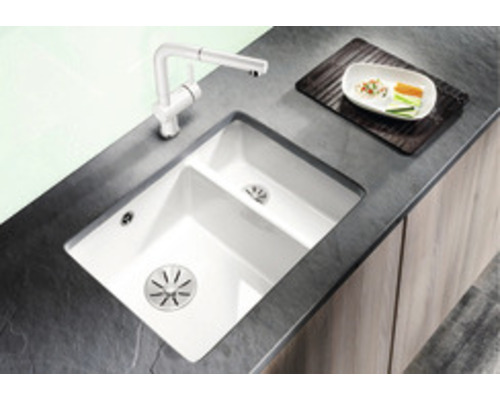 Keuken spoelbak met afdruiprek en kraan op donker aanrechtblad.