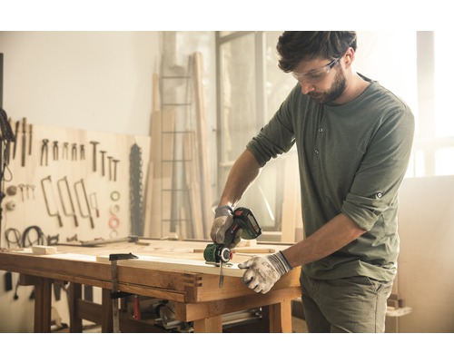Ambachtsman zaagt hout met een accusabelzaag in een werkplaats.