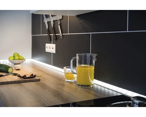 Keukenscène met sapkan, glas, snijplank en keukengerei voor een zwarte tegelachterwand