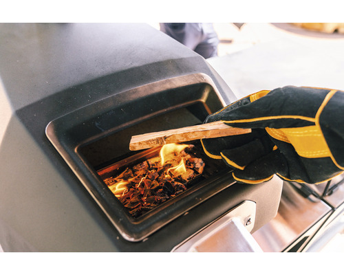 Iemand met handschoenen vult een oven met hout