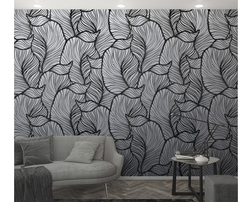 Woonkamer met behang met bladmotief, bank en bijzettafel.