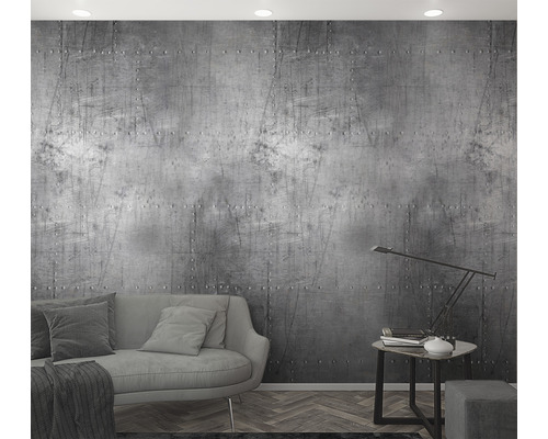 Woonkamer met een grijze bank en een muur met klinknagelmotief