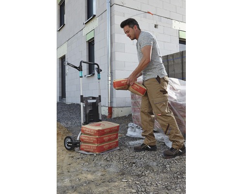 Man vervoert cementzakken met een steekwagen voor een huis