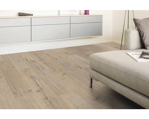 Woonkamer met lichte houten vloer, bank en ladekast