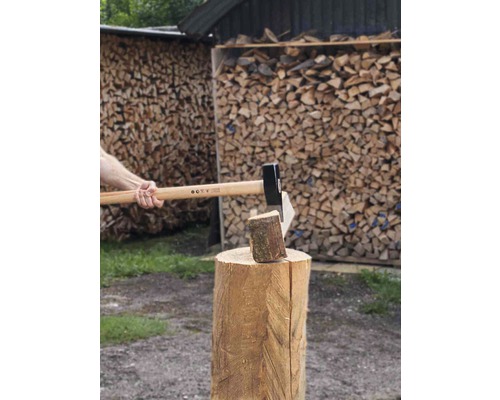Hout hakken met een bijl op een hakblok voor een stapel hout