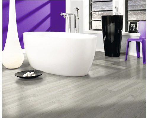 Badkamer met vrijstaand bad, zwarte wastafel, paarse stoel en lichte houten vloer