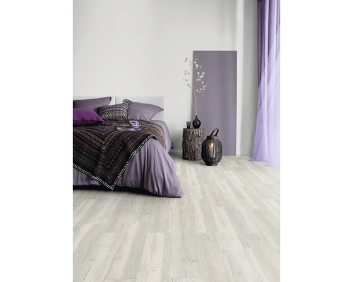 Slaapkamer met lichte houten vloer, bed, nachtkastje en decoraties.