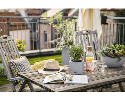 Balkonscène met houten tafel, stoelen, planten, boek, hoed en drankjes voor een ontspannen sfeer