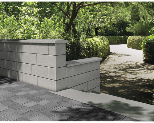 Tuinmuur van betonstenen met afdekking in een groene tuin