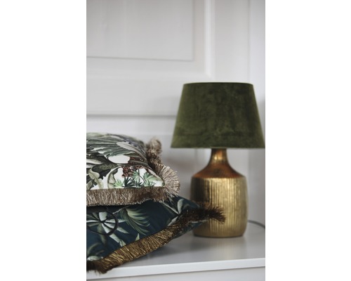 Decoratieve kussens met franjes en een tafellamp op een plank.