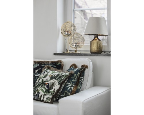 Decoratieve woonkamer met bank, kussens met jungle motieven, tafellamp en theelichthouders