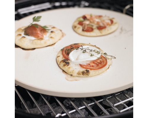 Pizzasteen met belegde mini-pizza''s op een barbecue