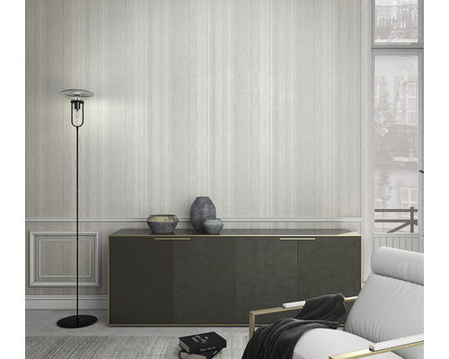 Woonkamer met staande lamp, dressoir en fauteuil voor een gestreept behang