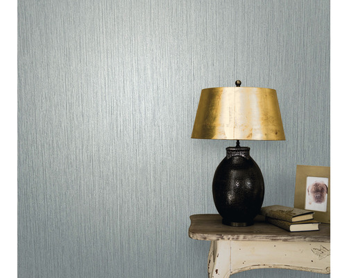 Close-up van een muur met structuurbehang naast een tafel met lamp