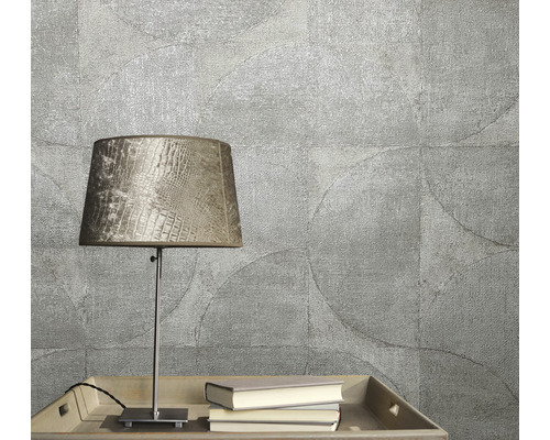 Close-up van een gestructureerd behang met cirkelmotief, aangevuld met een tafellamp en boeken op een dienblad