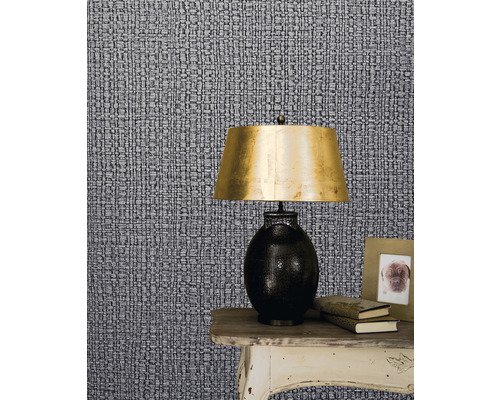 Close-up van een behang met patroon met een nachtkastje, een lamp, boeken en een fotolijst.