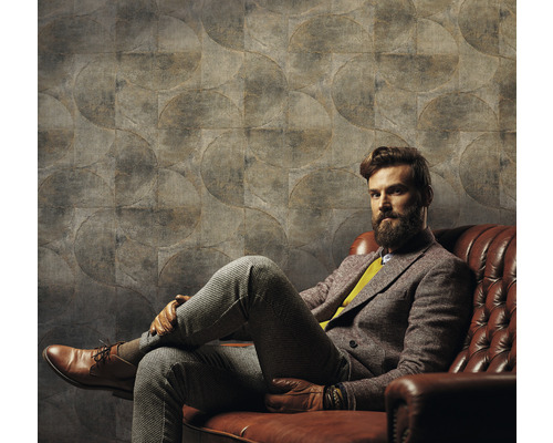 Man zit voor een muur met cirkelpatroonbehang op een leren bank