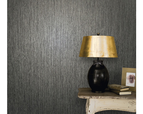 Close-up van een muur met structuurbehang, een tafel en een tafellamp.