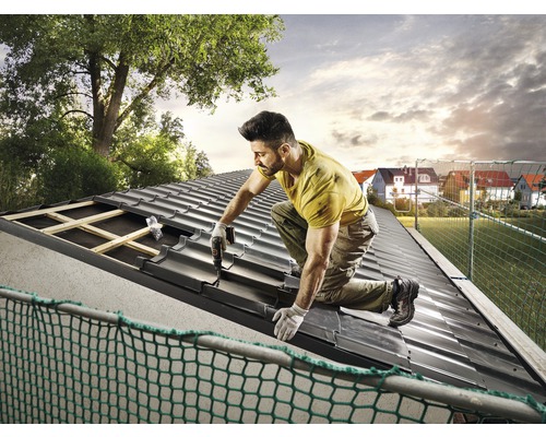 Een vakman bevestigt dakpannen op een dak.