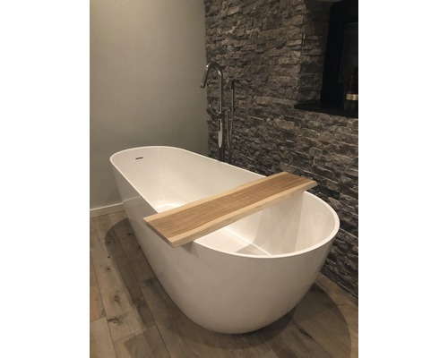 Vrijstaand bad met houten plank en kraan voor stenen muur