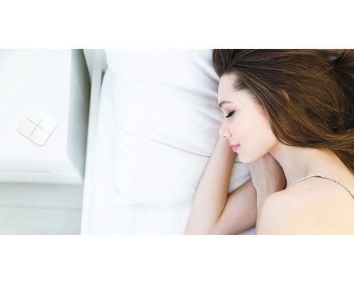 Vrouw slaapt in bed met smarthome-schakelaar op het nachtkastje