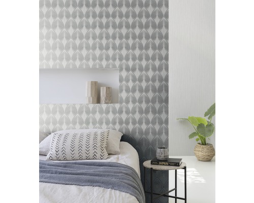 Slaapkamer met patroonbehang, bed en bijzettafel.