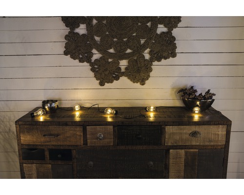 Dressoir met lades, decoratie en lichtsnoer voor een houten wand