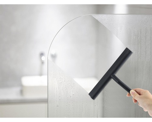 Hand veegt een douchewand droog met een wisser