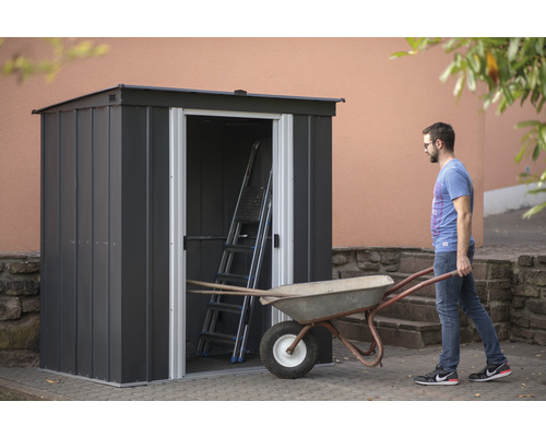 Tuinkast met open deur, ladder en kruiwagen in de tuin