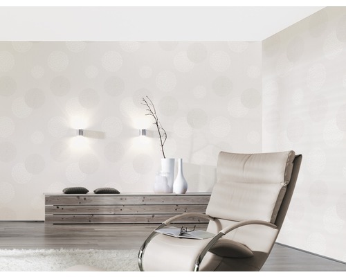 Woonkamer met patroonbehang, fauteuil en houten dressoir