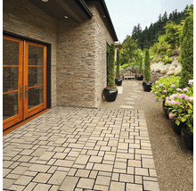 Buitenkant met vloerplaten, huiswand met steenbekleding en beplanting