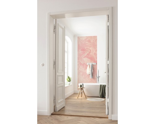 Badkamer met ligbad, kruk, handdoeken en een roze fotobehang met drakenmotief.