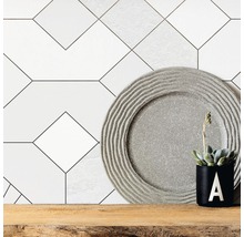 Decoratieve wandtegels met geometrisch patroon, decoratief bord en potplant op houten plank.