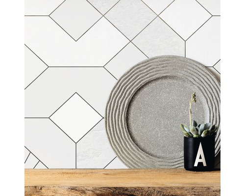 Decoratieve wandtegels met geometrisch patroon, decoratief bord en potplant op houten plank.