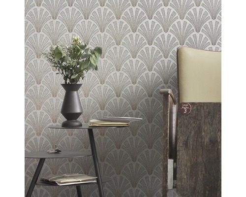 Close-up van een muur met een behang met een waaiervormig patroon in een kamer met een tafel en een stoel