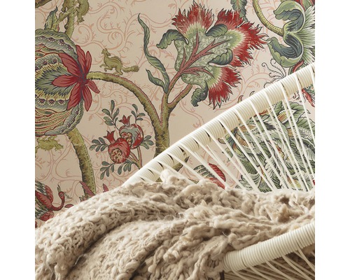 Detail van een kamer met een behang met print, een stoel en een deken.