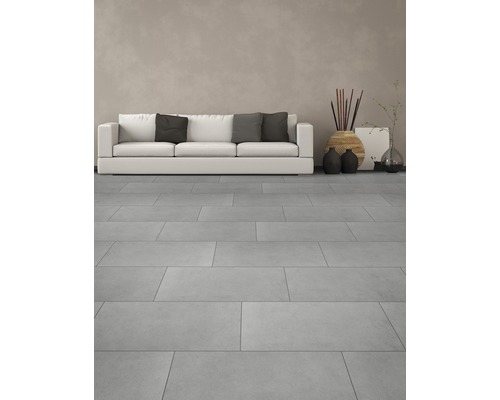 Lichte woonkamer met vloertegels, bank en decoraties.